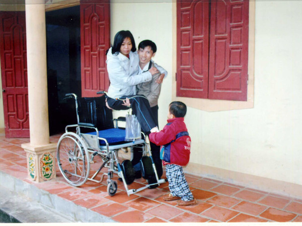 Anh Chín bế chị Phương lên xe lăn