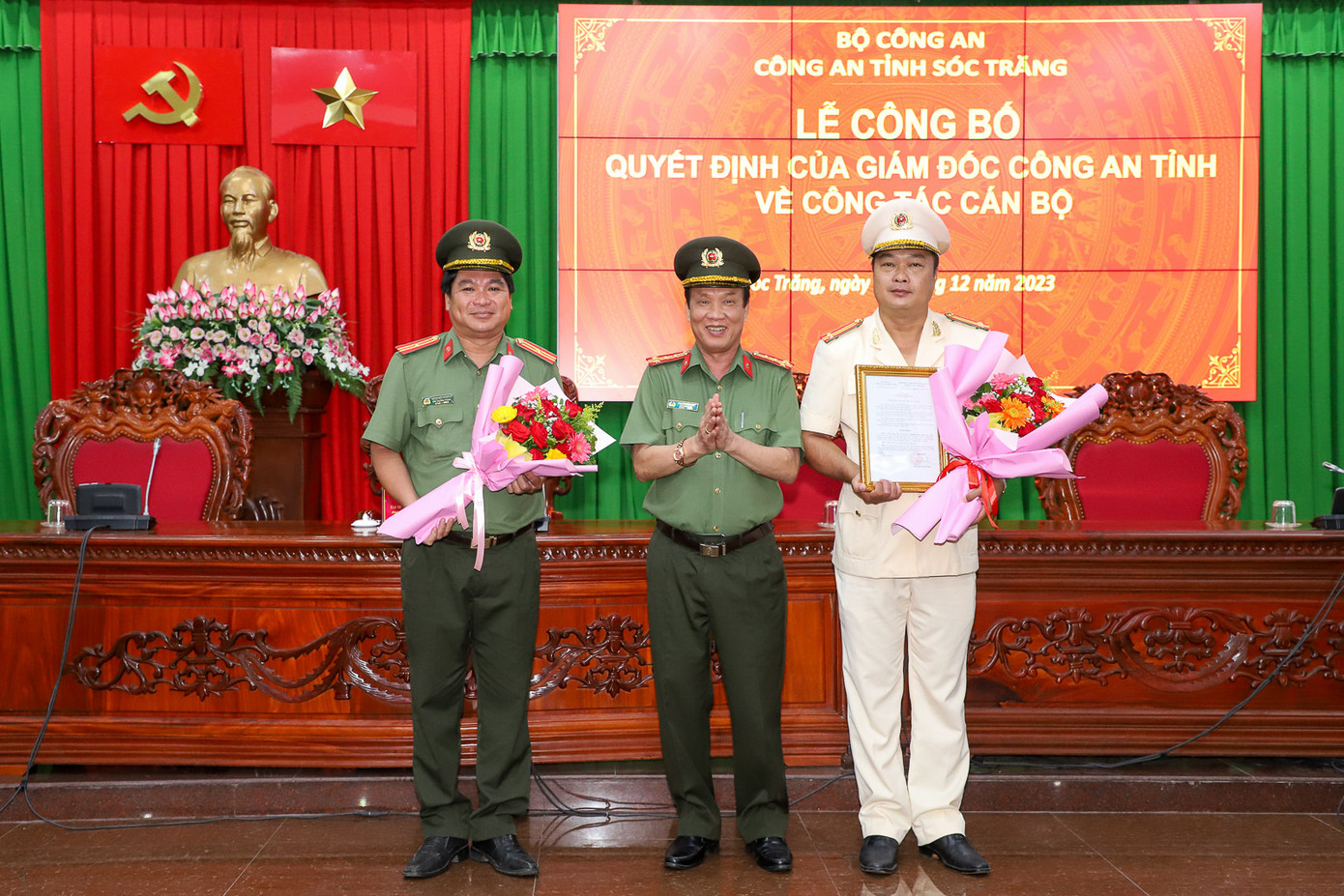 Đại tá Phạm Quốc Việt - Phó Giám đốc Công an tỉnh Sóc Trăng trao quyết định điều động đối với Trung tá Nguyễn Ngọc Lành (bìa phải) và tặng hoa chúc mừng Thiếu tá Đặng Văn Phương. Ảnh: Báo Sóc Trăng