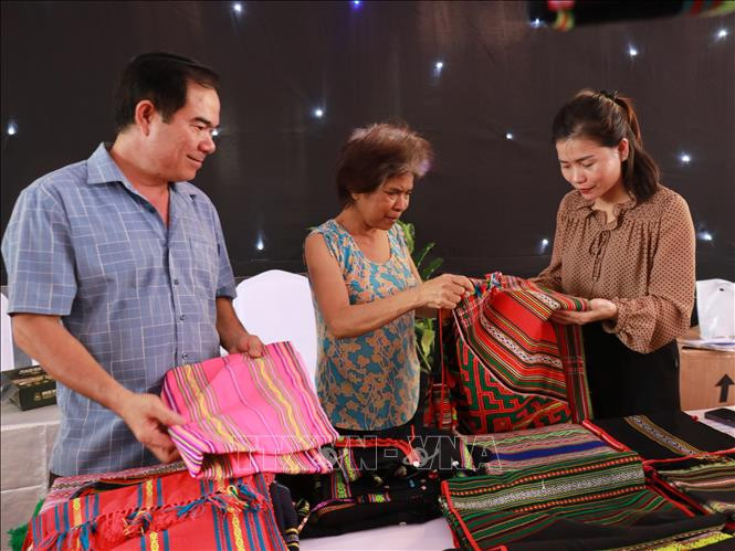 Bà Thị An Đê, Bù Đăng, Bình Phước (phải) giới thiệu sản phẩm thổ cẩm dân tộc thiểu số cho khách tham quan. Ảnh: TTXVN Bà Thị An Đê, Bù Đăng, Bình Phước (phải) giới thiệu sản phẩm thổ cẩm dân tộc thiểu số cho khách tham quan. Ảnh: TTXVN