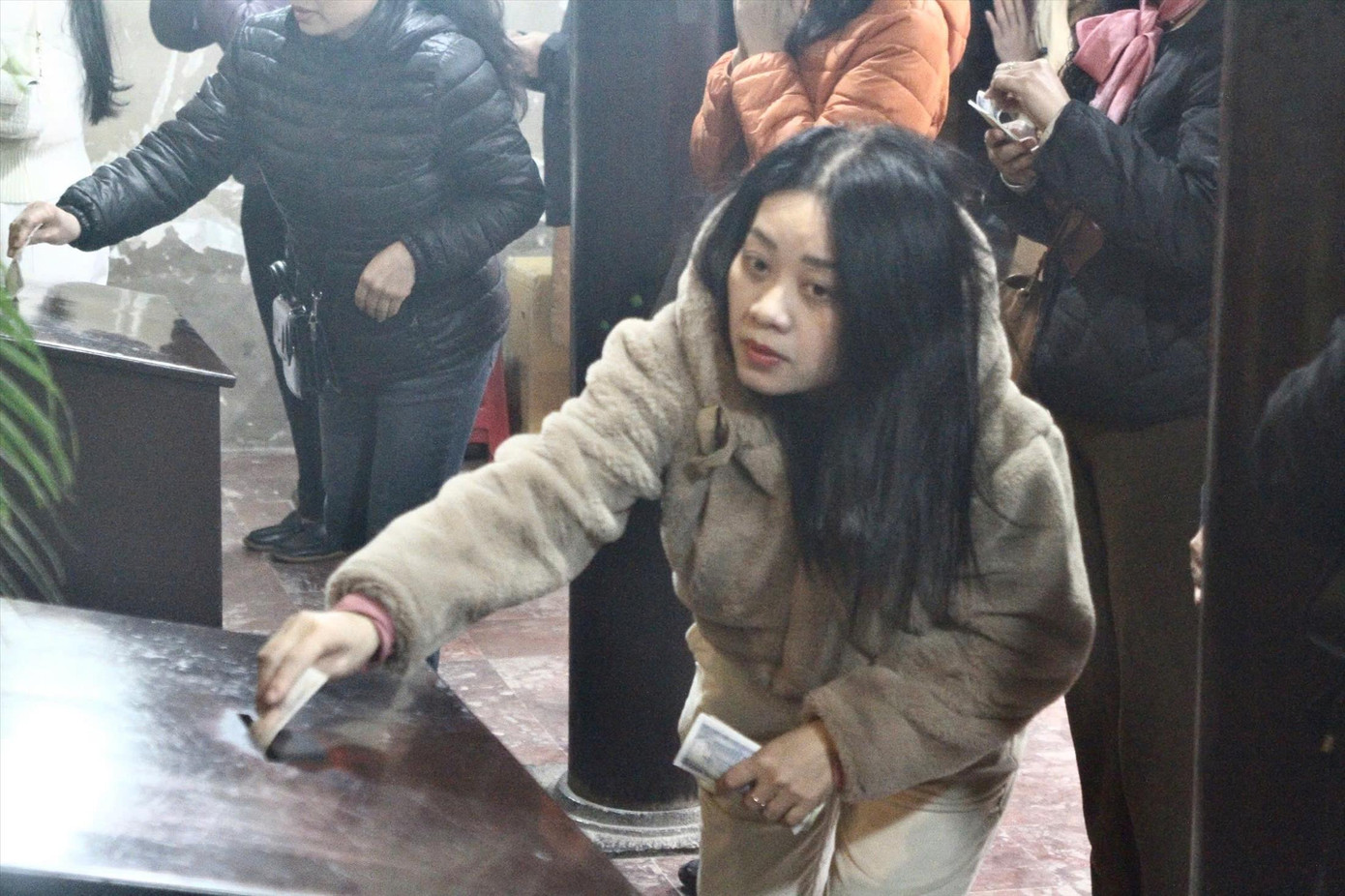 Người dân bỏ tiền công đức vào hòm khi đi lễ tại chùa Phúc Khánh (quận Đống Đa, TP Hà Nội)