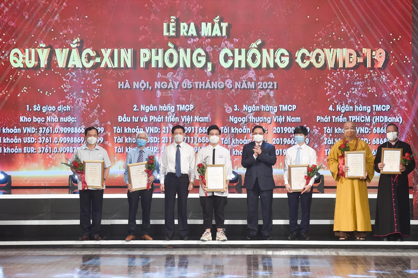 Thủ tướng Phạm Minh Chính tặng hoa cảm ơn các nhà hảo tâm đã đóng góp cho Quỹ phòng, chống COVID-19. Ảnh: Như Ý