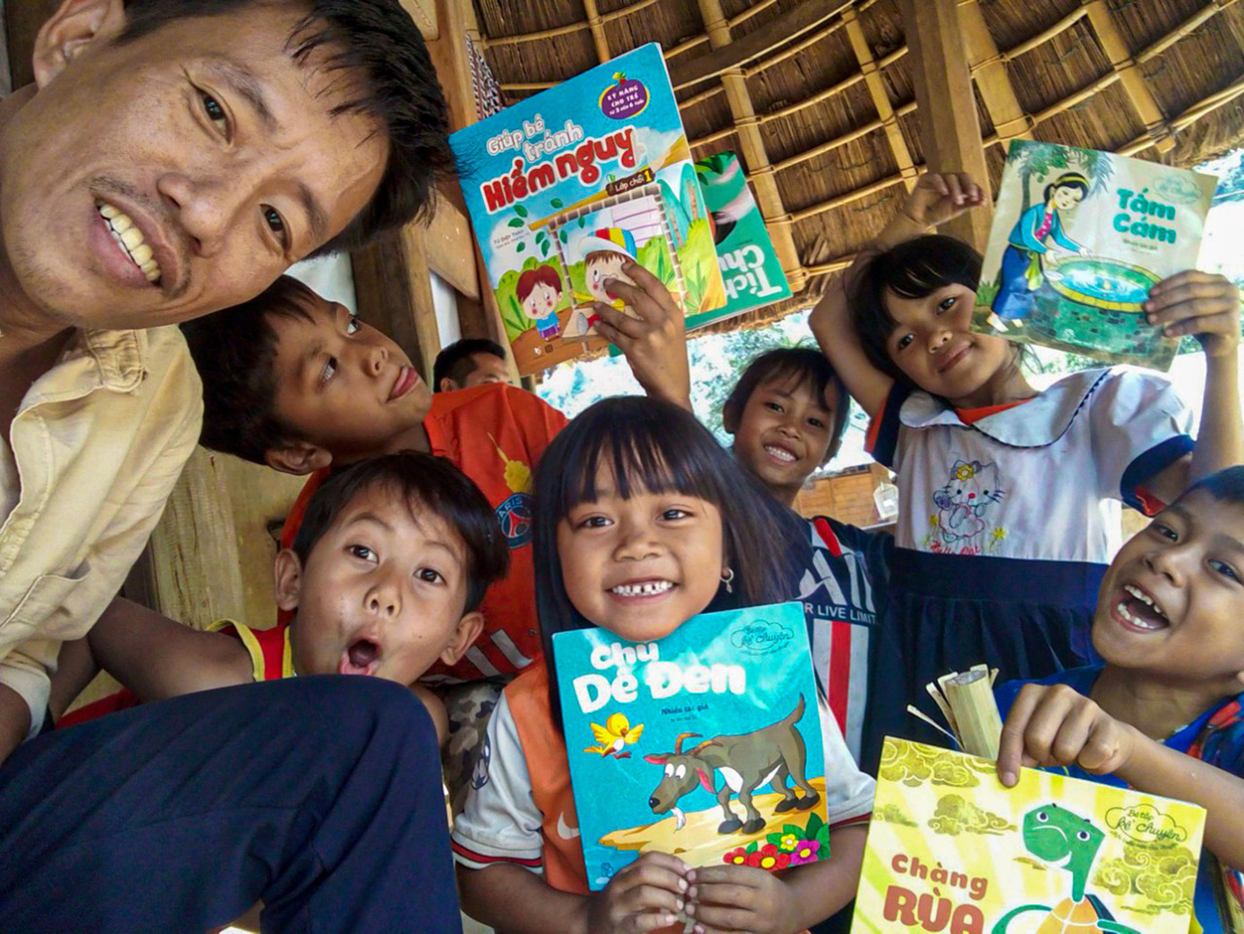 Tác giả và các em nhỏ vùng biên giới thích thú với những cuốn truyện tranh lần đầu biết đến. Ảnh: Nguyễn Thành Tác giả và các em nhỏ vùng biên giới thích thú với những cuốn truyện tranh lần đầu biết đến. Ảnh: Nguyễn Thành