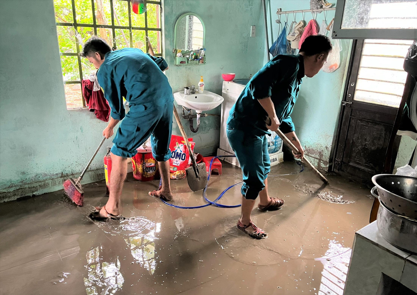 Lực lượng dân quân giúp người dân dọn bùn đất tràn vào nhà. Ảnh: T.T