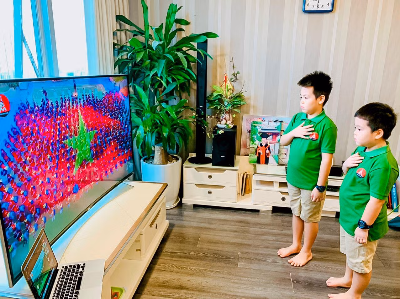 Học sinh Hà Nội chào cờ qua tivi trong lễ khai giảng năm học mới. Ảnh: Quỳnh Anh