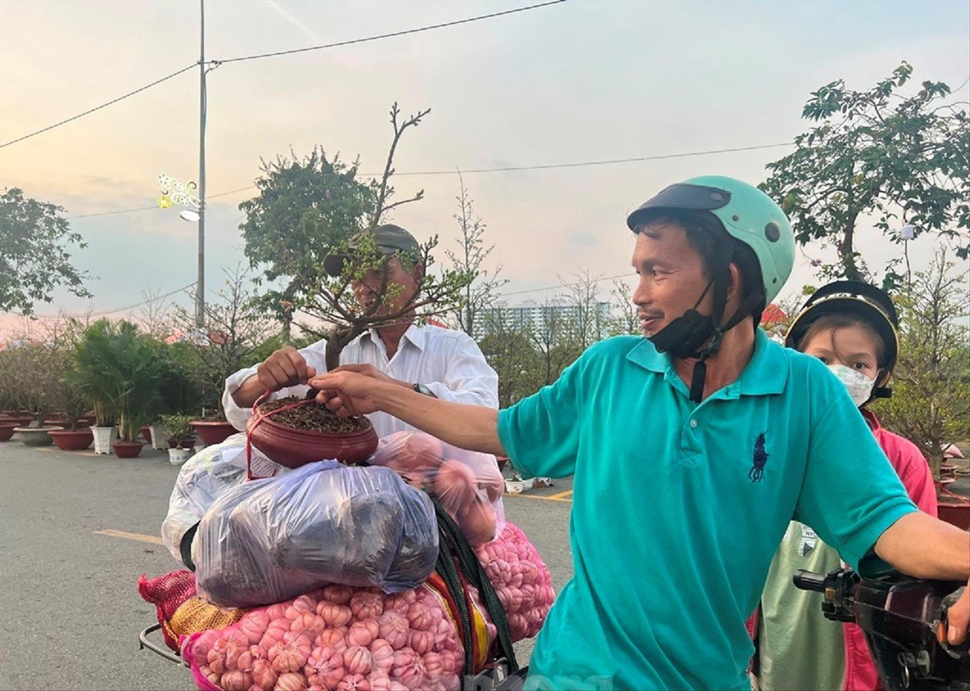 Người chở hàng ở chợ đầu mối Bình Điền vui mừng mua được chậu mai giá rẻ về đón Tết. Ảnh: U.P