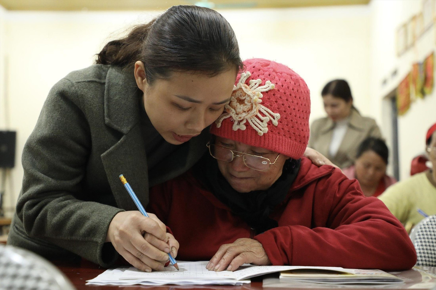 Giáo viên cầm tay nắn chữ cho cụ bà