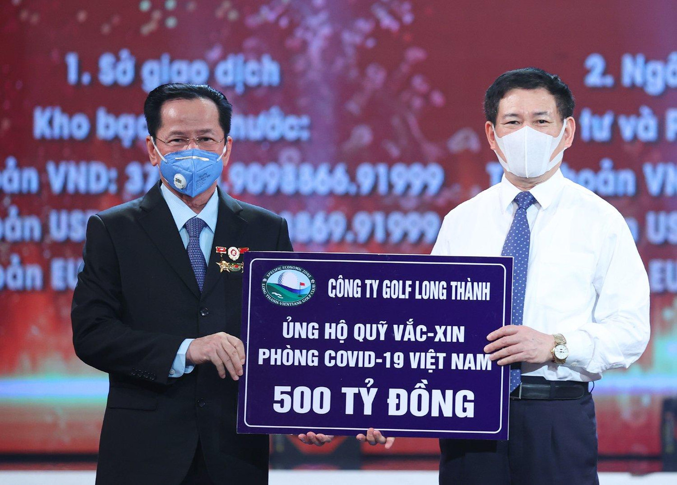 Anh hùng lao động Lê Văn Kiểm (bìa trái) trao 500 tỷ đồng cho Quỹ Vắc-xin