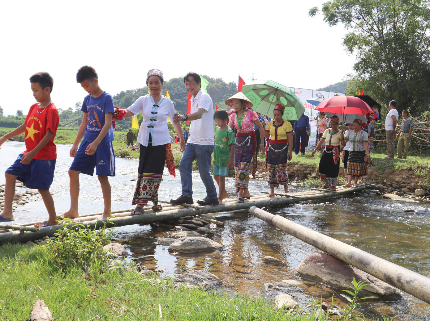 Nhà báo Lê Minh Toản - Phó Tổng Biên tập báo Tiền Phong cùng người dân đi trên chiếc cầu tạm ngày khởi công cầu ở huyện Con Cuông (Nghệ An)