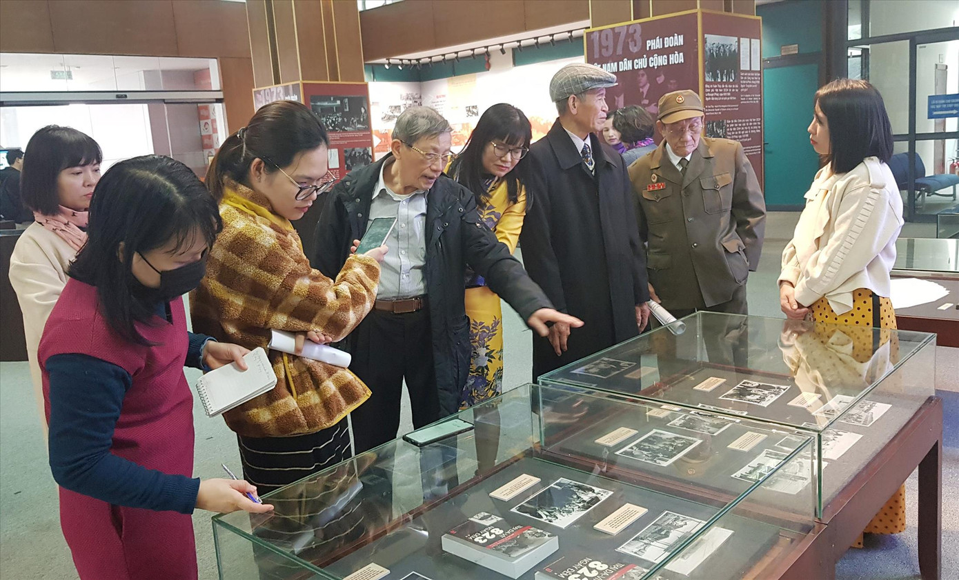 Đại tá Đinh Quốc Kỳ (thứ 3 từ trái sang) và CCB Phạm Văn Lãi (thứ 5) trao đổi với các phóng viên bên tủ trưng bày về các hoạt động của Trại Davis. Ảnh: Kiến Nghĩa