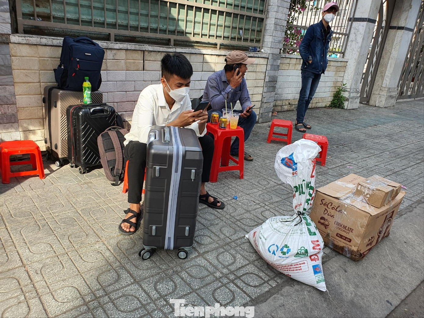 Một sinh viên cùng bố ngồi trước cổng trường đại học ở TPHCM chờ tìm phòng trọ