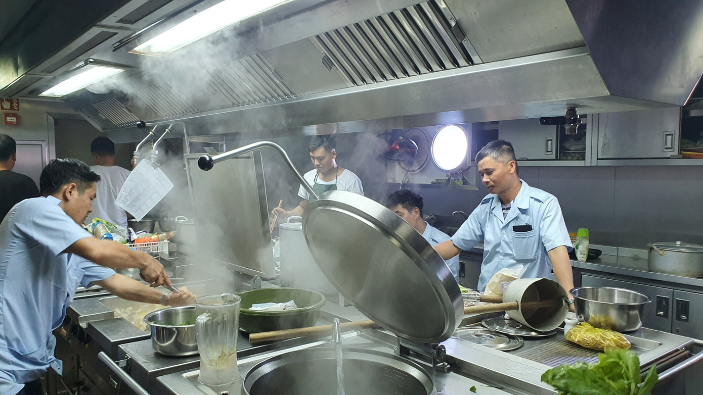 Bếp trưởng Trần Đức Hưng (bìa trái) và tổ phục vụ đang nấu ăn. Ảnh: Nguyễn Tuấn