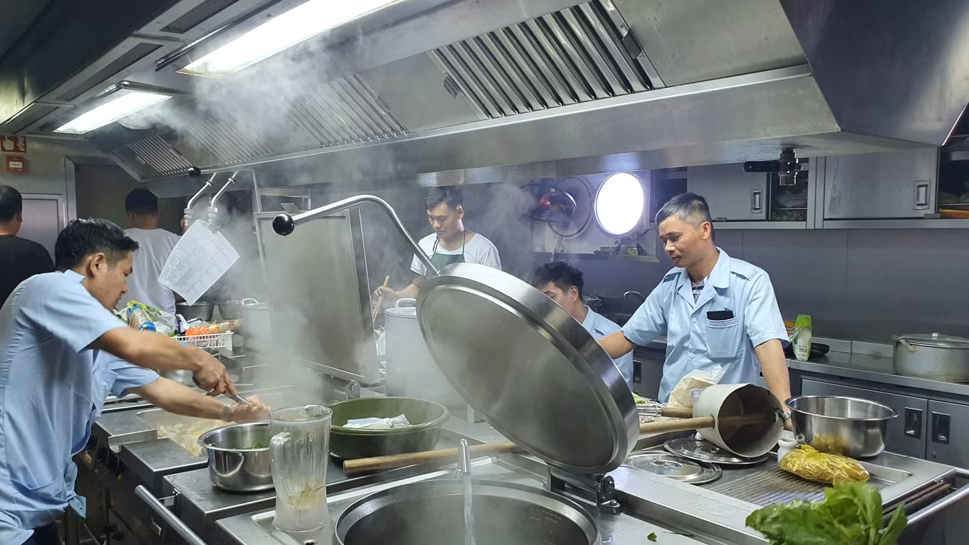 Bếp trưởng Trần Đức Hưng (bìa trái) và tổ phục vụ đang nấu ăn. Ảnh: Nguyễn Tuấn