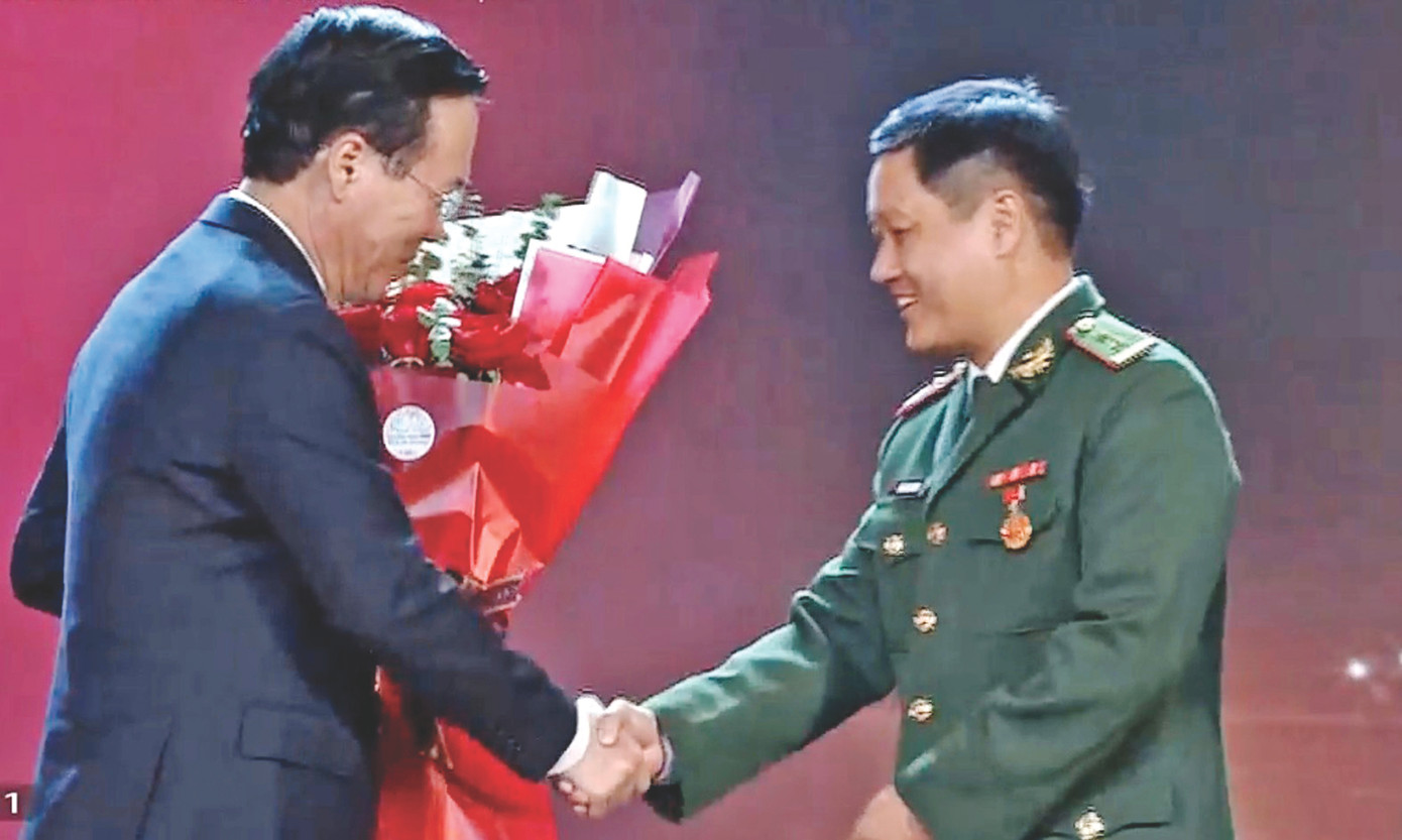 Trung tá Đặng Hùng Cường (bìa phải) nhận hoa chúc mừng mô hình “Lũy tre biên giới Việt” từ Chủ tịch nước Võ Văn Thưởng. Ảnh: Duy Chiến