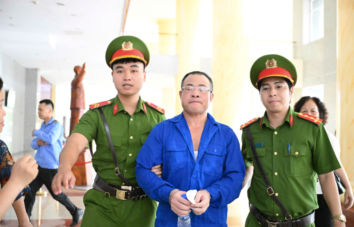 Bị cáo Nghiêm Quang Minh bị dẫn giải tới tòa án. Bị cáo Nghiêm Quang Minh bị dẫn giải tới tòa án.