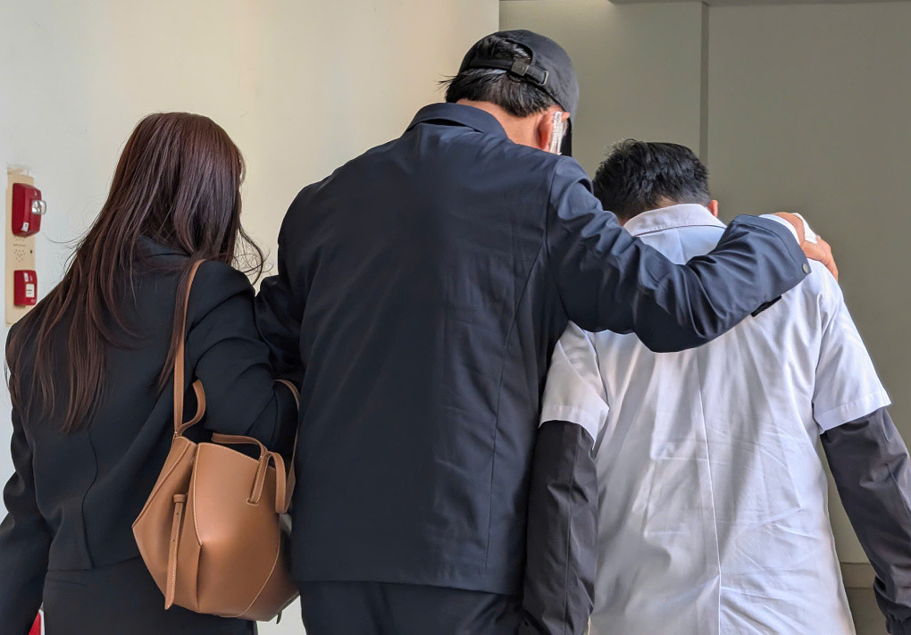 Bị cáo Mai Tiến Dũng (đội mũ) được tại ngoại, được hai người dìu vào phòng xử án theo lối cửa riêng.