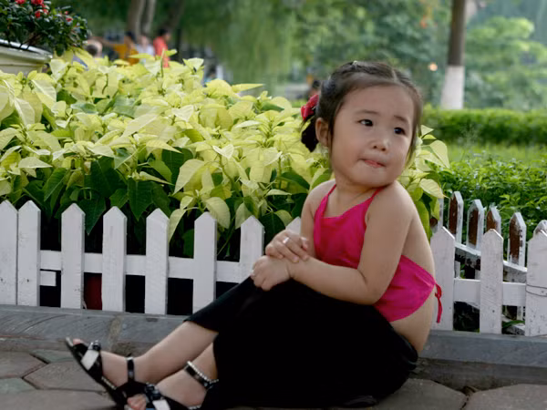 Em bé đang nghiêng mình bên những bông hoa rưc rỡ