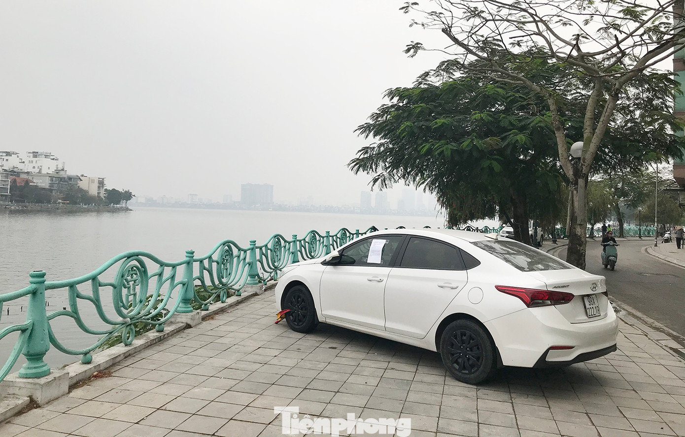 Một chiếc ôtô dừng đỗ trên vỉa hè ven hồ Tây bị lực lượng chức năng phường Quảng An khóa bánh, gắn giấy thông báo để chủ xe liên hệ làm việc. Ảnh: Trường Phong. Một chiếc ôtô dừng đỗ trên vỉa hè ven hồ Tây bị lực lượng chức năng phường Quảng An khóa bánh, gắn giấy thông báo để chủ xe liên hệ làm việc. Ảnh: Trường Phong.