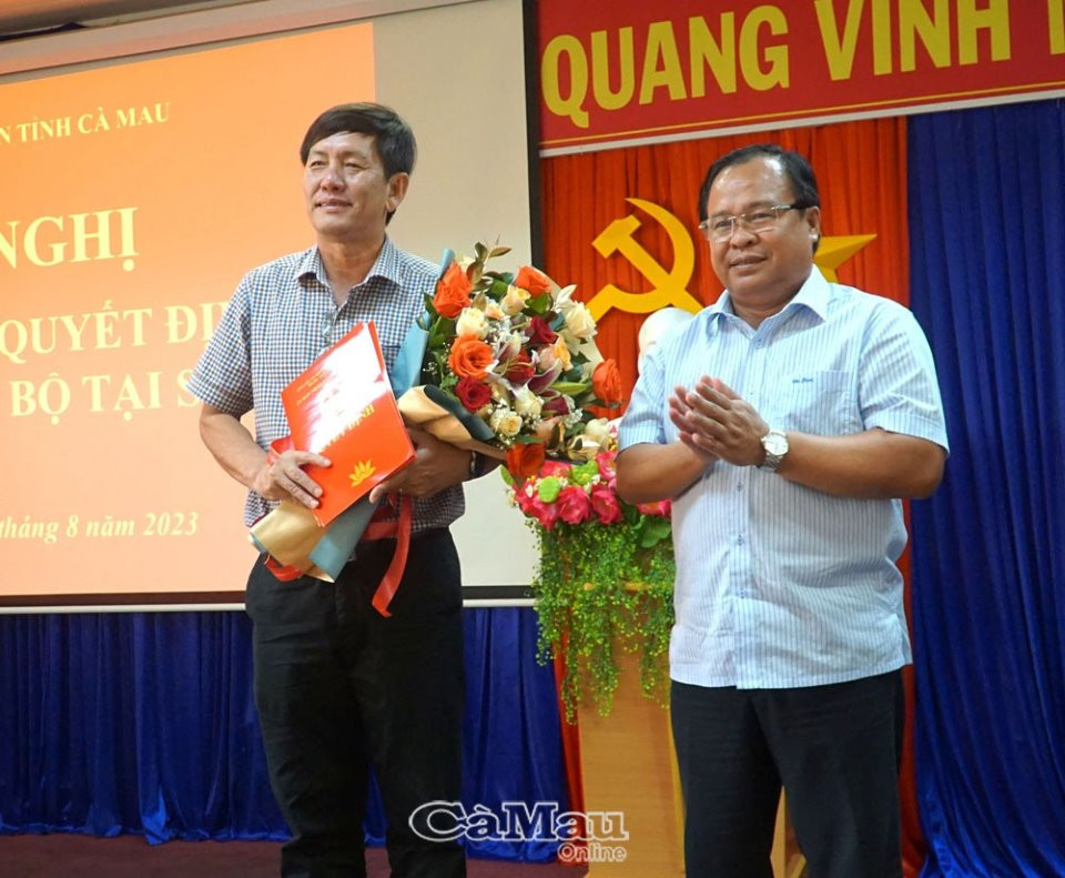 Ông Nguyễn Minh Luân, Phó Chủ tịch UBND tỉnh Cà Mau trao quyết định và tặng hoa chúc mừng ông Dư Minh Hùng. Ảnh: Báo Cà Mau.