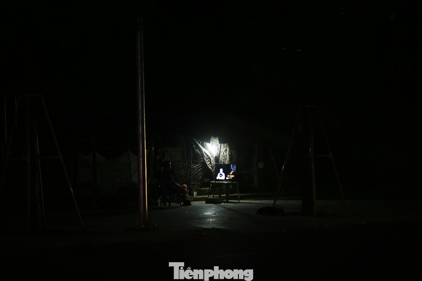 Dưới chân một cột đèn chiếu sáng trên tuyến đường Huỳnh Thúc Kháng kéo dài, chỉ có ánh sáng phát ra từ một chiếc ti vi.