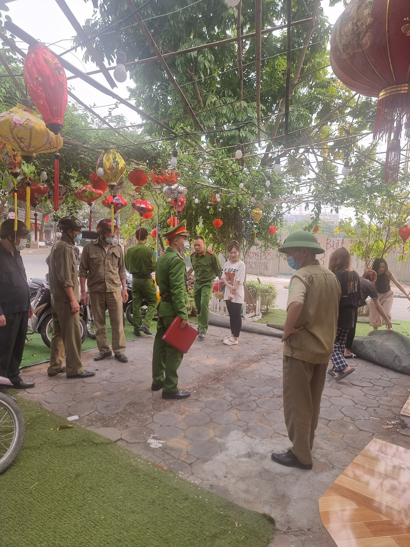 Lực lượng chức năng phường Hoàng Liệt yêu cầu chủ quán cà phê vi phạm vỉa hè phải tháo dỡ, dọn dẹp các vật dụng lấn chiếm vỉa hè. Ảnh: Công an phường Hoàng Liệt cung cấp.