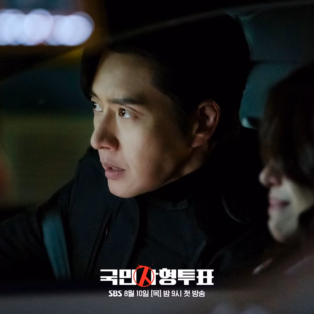 Kim Moo Chan (Park Hae Jin) đang ngồi ở ghế phụ trong ô tô của ai đó. Biểu cảm khuôn mặt của anh ấy truyền tải sự cảnh giác và căng thẳng cùng một lúc.