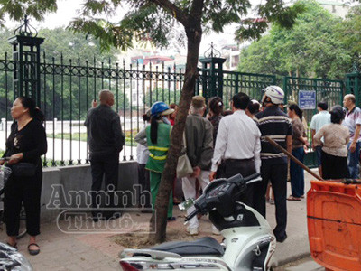 Người dân tụ tập phía ngoài hàng rào, nhìn vào khu vực hồ, nơi có thi thể nạn nhân