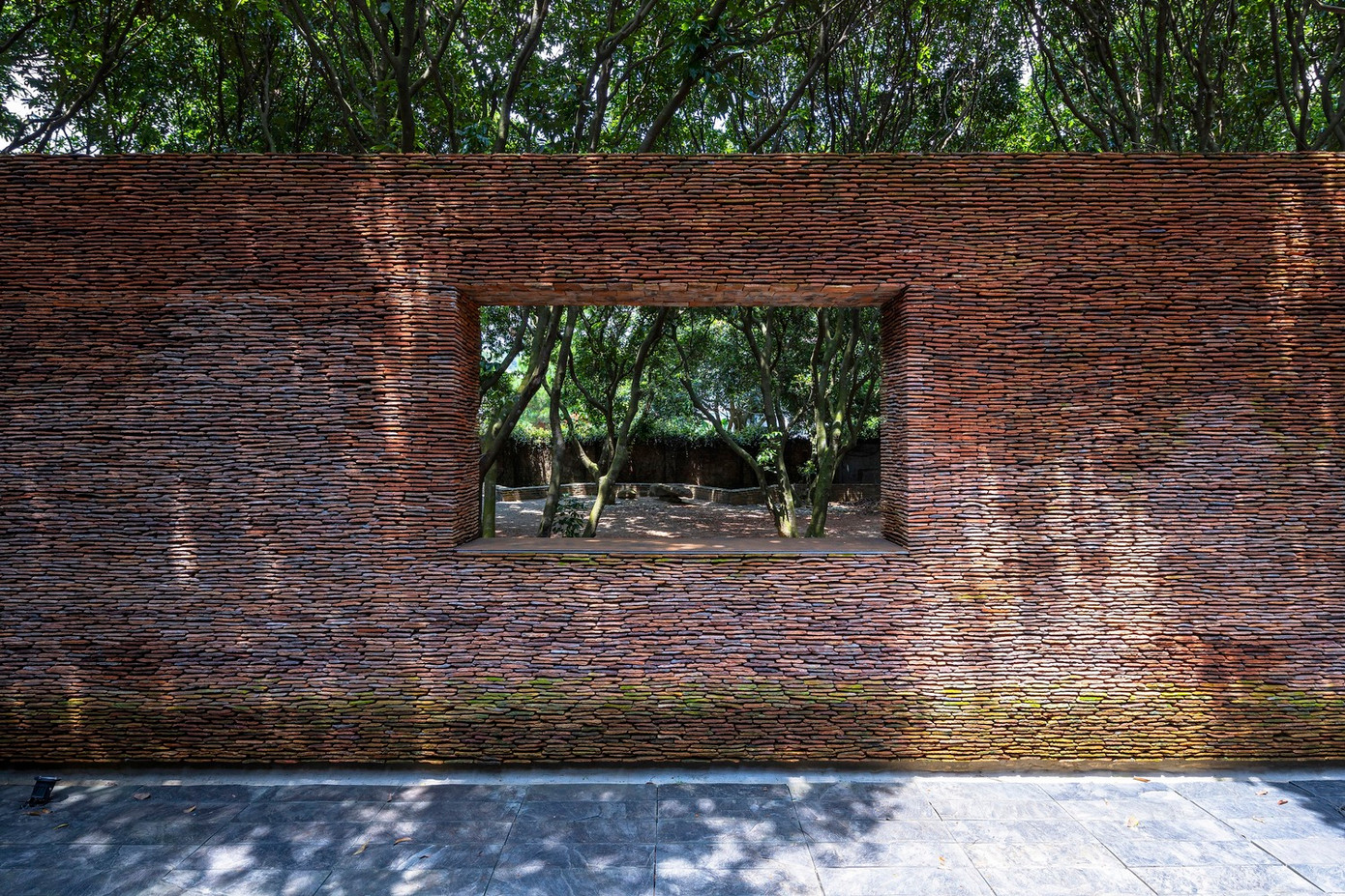 Nhìn từ bên ngoài, vườn cây ăn trái cổ thụ như được đóng khung và che giấu cẩn thận sau cổng, tạo nên một kiến trúc vừa tách biệt vừa hài hòa với khung cảnh xung quanh địa phương.