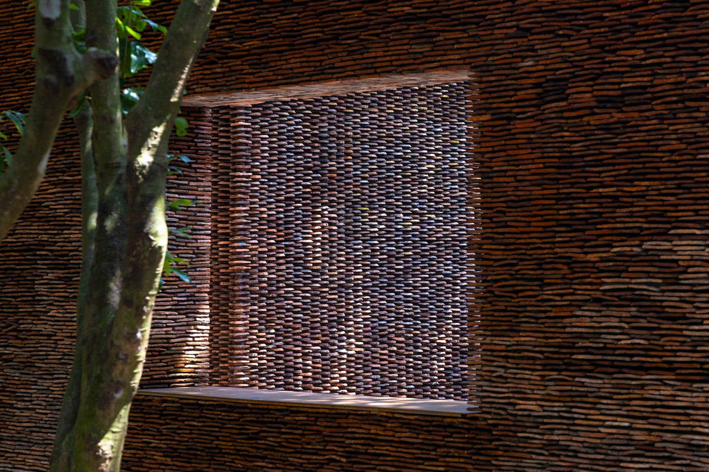 Nhìn từ bên ngoài, vườn cây ăn trái cổ thụ như được đóng khung và che giấu cẩn thận sau cổng, tạo nên một kiến trúc vừa tách biệt vừa hài hòa với khung cảnh xung quanh địa phương.