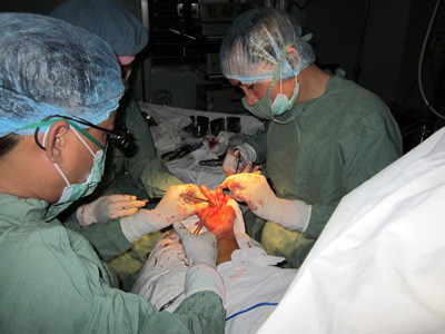 Bác sĩ Phan Dzư Lê Thắng đang mổ một ca đứt lìa tay qua kính hiển vi nhưng cuộc mổ kéo dài 6 tiếng này anh chỉ được trả 50-65.000 đồng