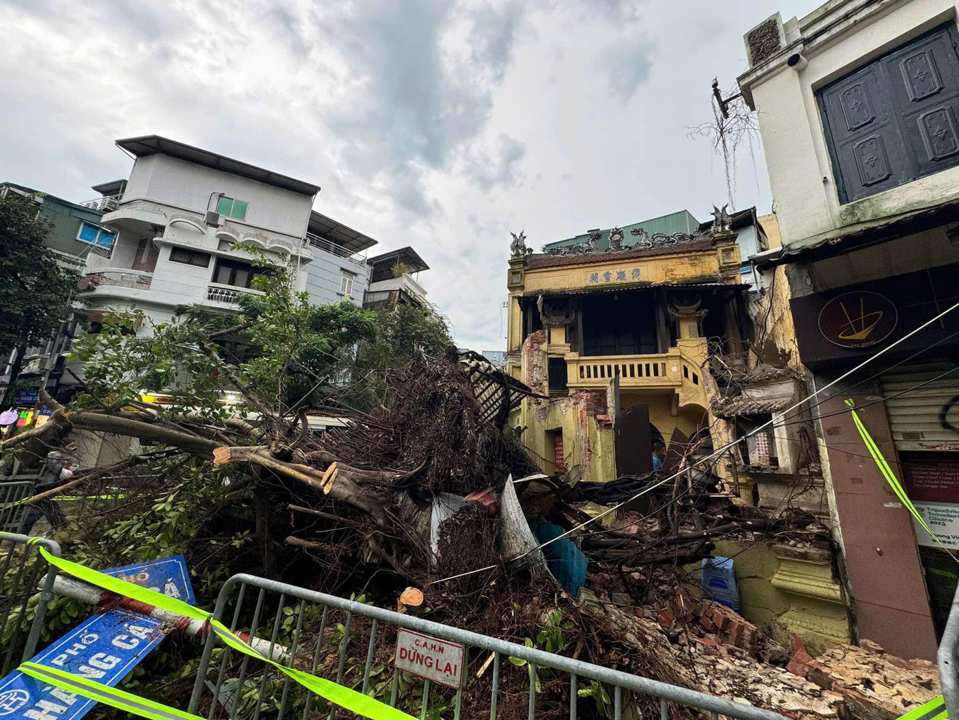 Cây đổ kéo sập nhà trên phố Chả Cá, phải cưa cây để cứu người ra.