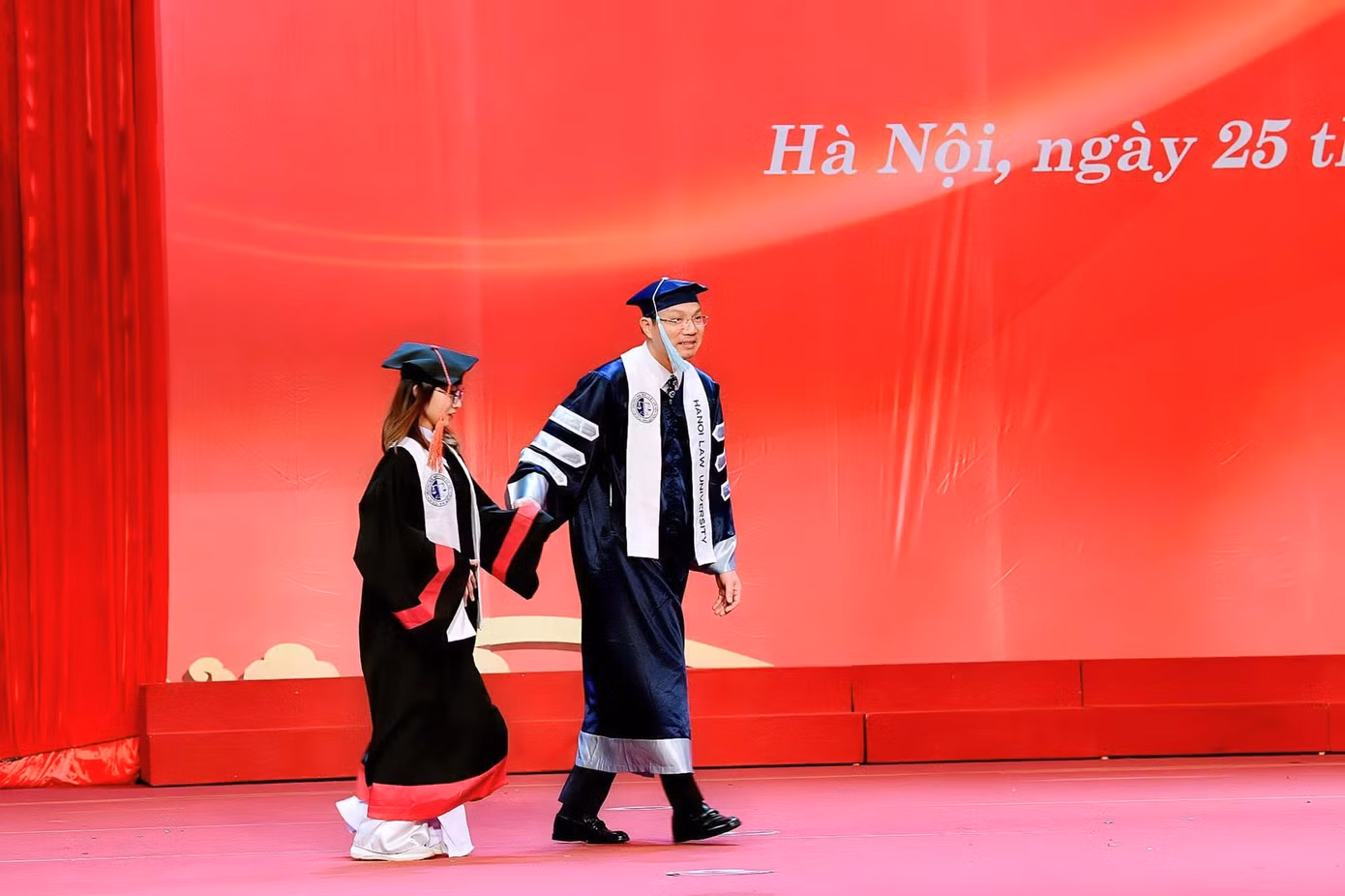 Thầy Hiệu trưởng dắt tay nữ sinh Mai Anh ra sân khấu.