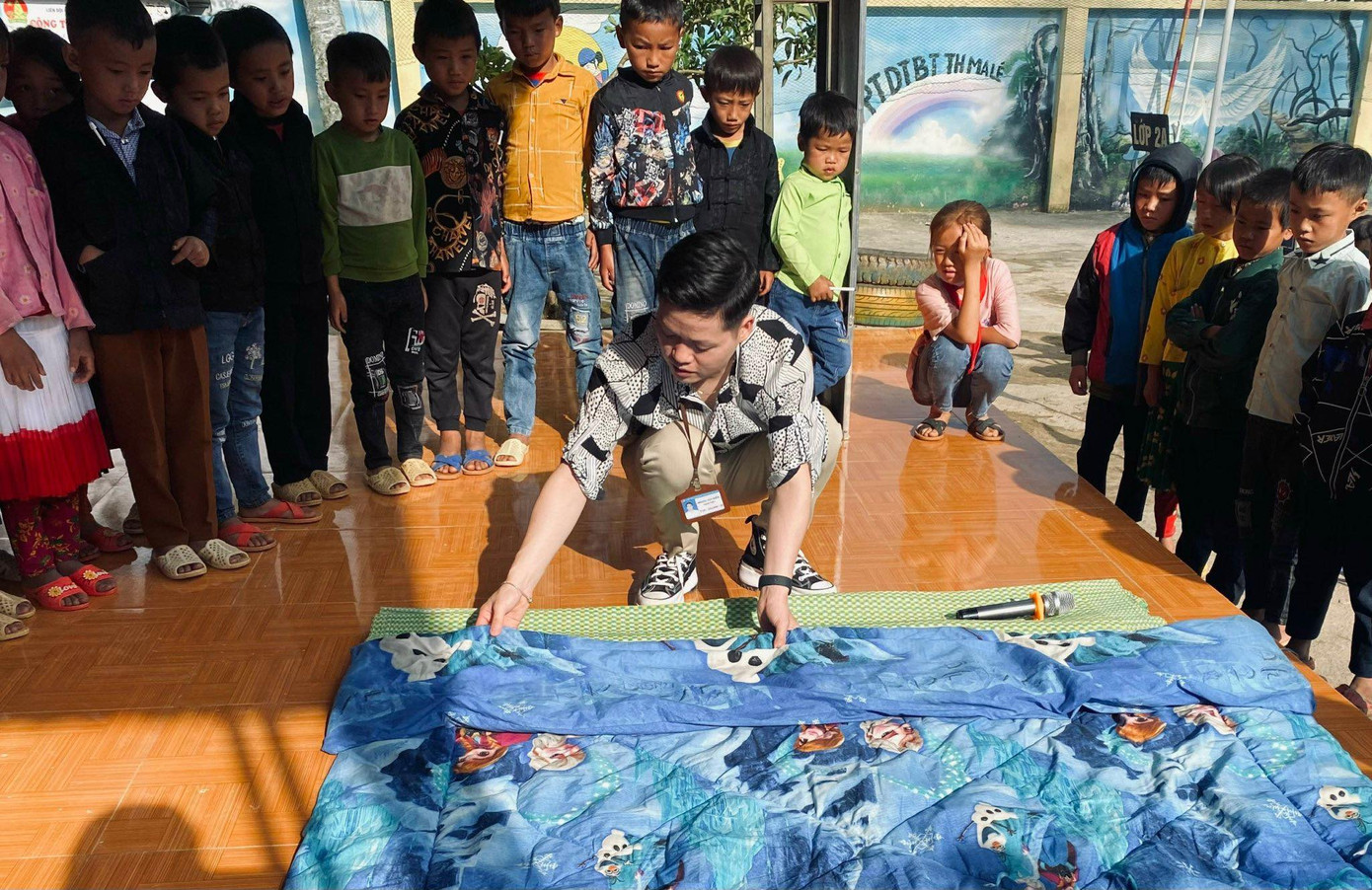 Thầy giáo Hoàng Diễm hướng dẫn các em học sinh vùng cao cách gấp chăn màn.