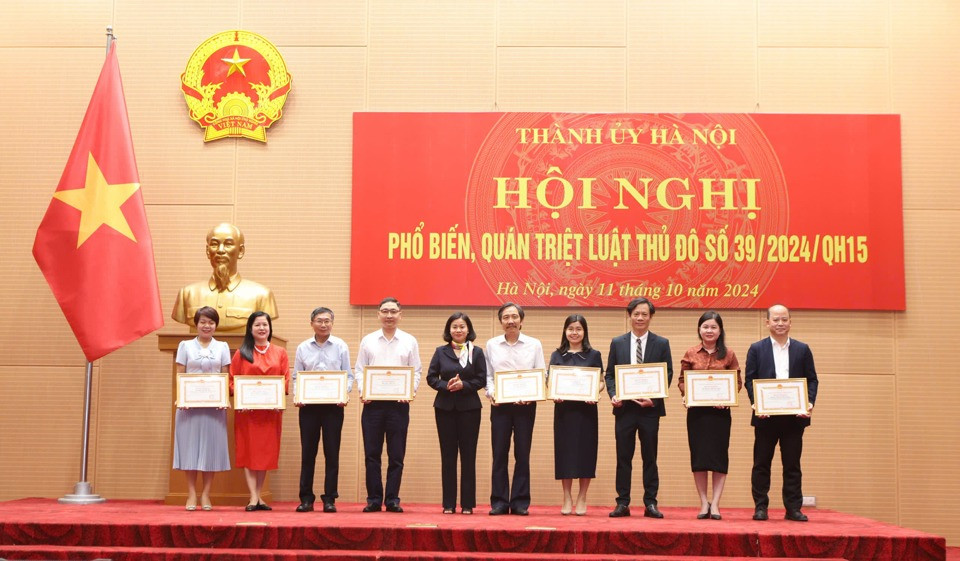 Phó Bí thư Thường trực Thành ủy Hà Nội Nguyễn Thị Tuyến (thứ 5, từ trái sang) trao Bằng khen cho các Tập thể có thành tích xuất sắc trong công tác xây dựng, ban hành Luật Thủ đô năm 2024.
