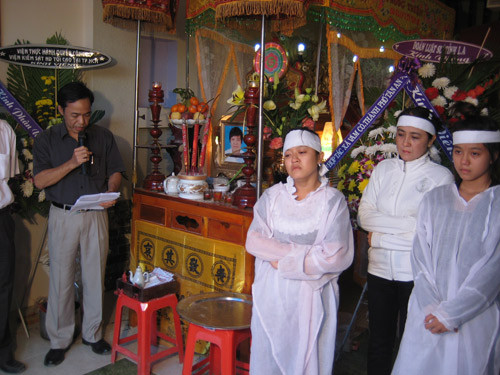 Bà Liễu (đứng giữa hai con) trong đám tang nhà báo Hoàng Hùng