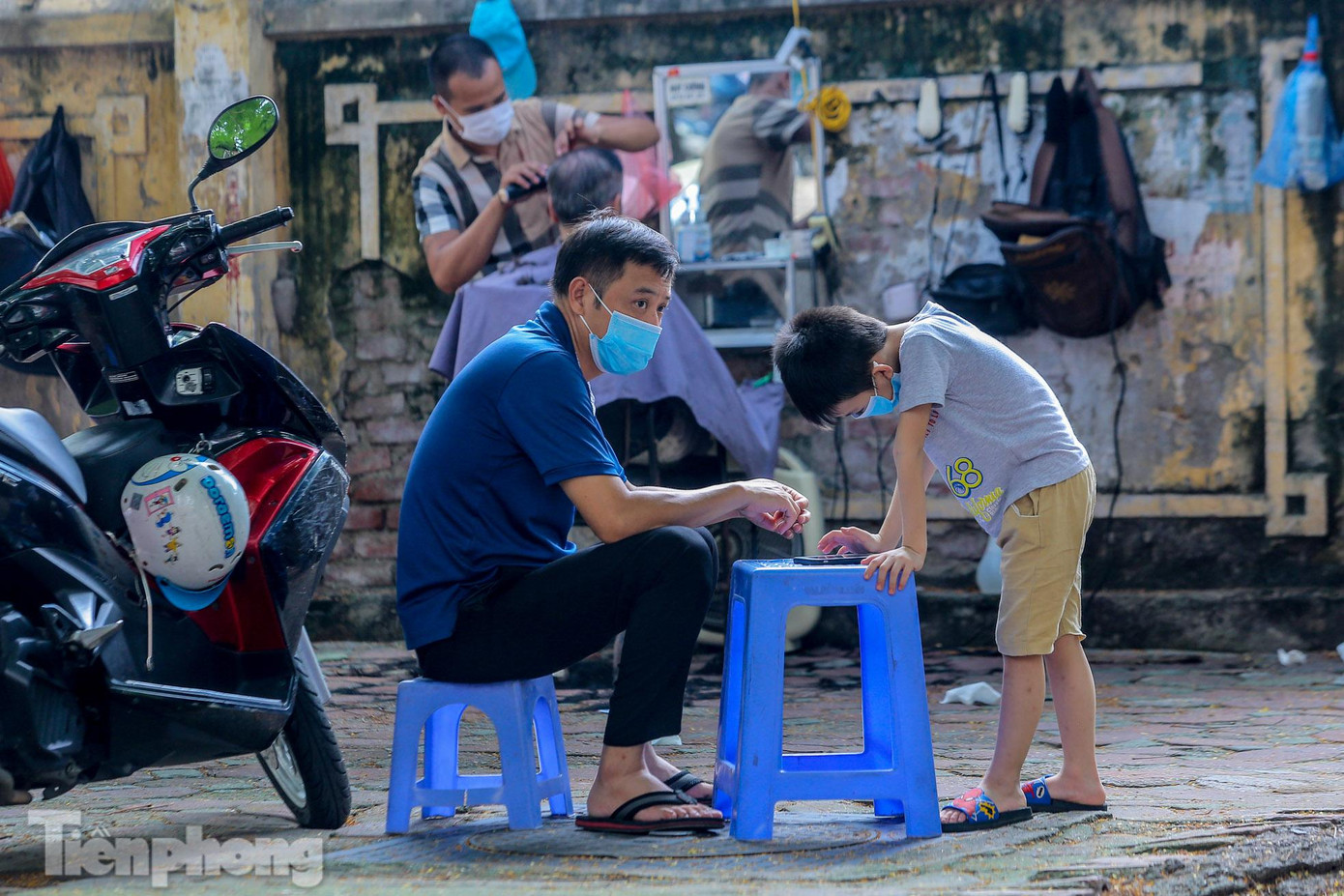 Hai bố con chờ đến lượt cắt tóc trên vỉa hè phố Thái Thịnh. Hai bố con chờ đến lượt cắt tóc trên vỉa hè phố Thái Thịnh.