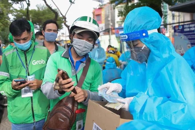Trước khi xét nghiệm, các shipper của Grab sẽ đưa tiền để lấy mẫu xét nghiệm