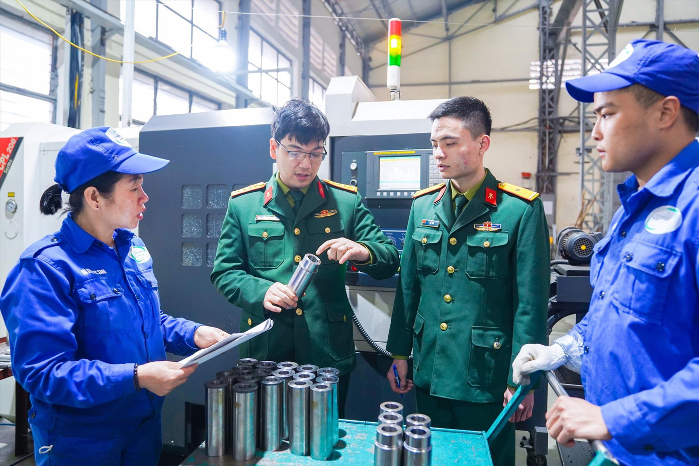 Đại úy Trần Minh Tuyên (thứ hai từ trái qua) hướng dẫn quy trình công nghệ gia công vỏ đầu đạn cao xạ cho công nhân nhà máy Z183 Đại úy Trần Minh Tuyên (thứ hai từ trái qua) hướng dẫn quy trình công nghệ gia công vỏ đầu đạn cao xạ cho công nhân nhà máy Z183