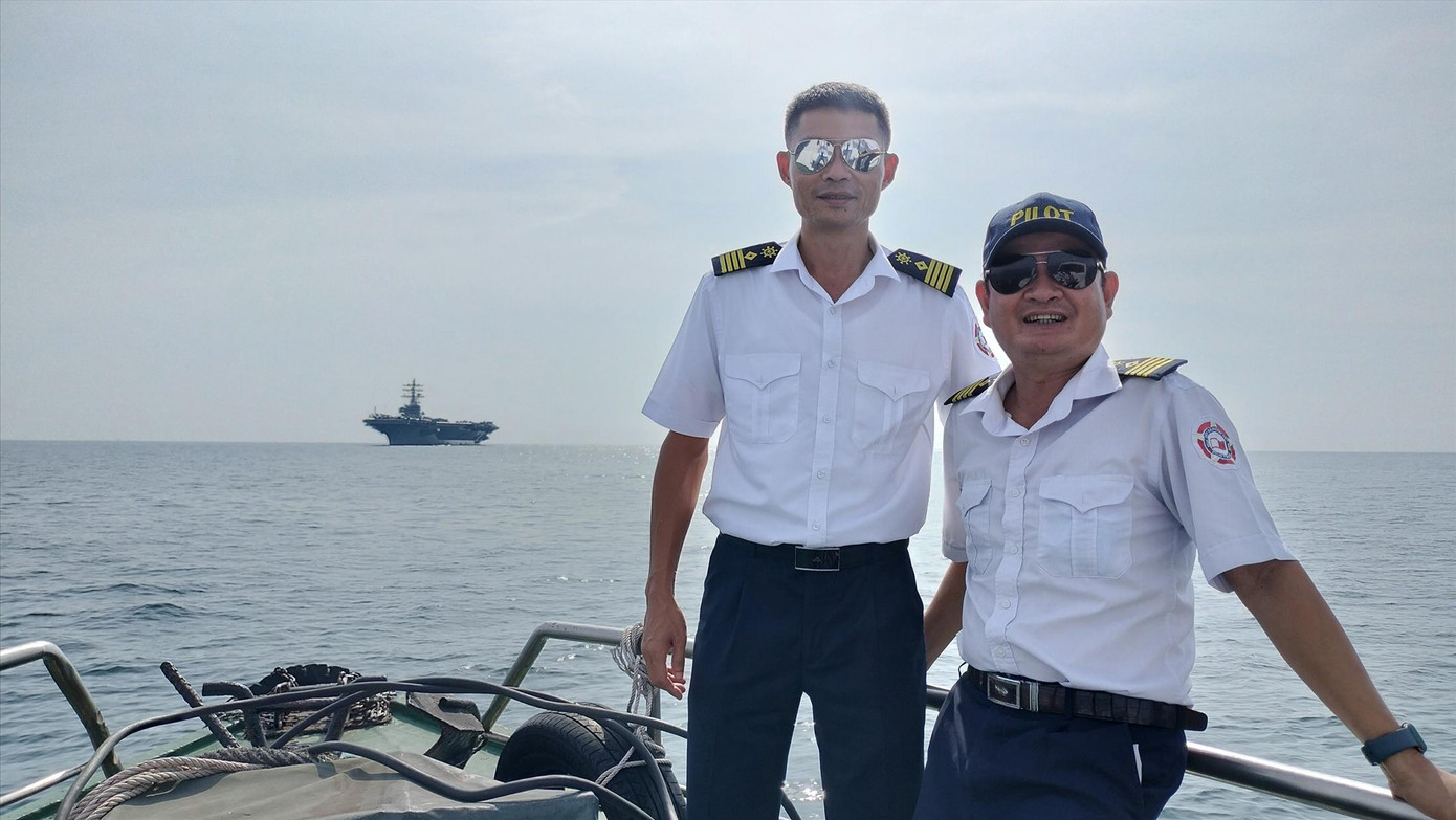 Hoa tiêu Hoàng Việt và Trần Cơ làm nhiệm vụ và chào đón đội tàu sân bay USS Ronald Reagan giữa biển khơi. Ảnh: Nguyễn Thành