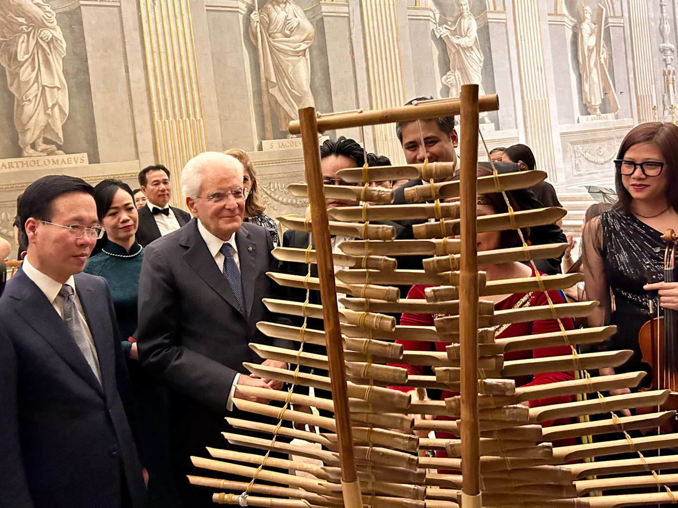 Tổng thống Italia Sergio Mattarella lên sân khấu xem các nhạc cụ dân tộc Việt Nam đàn bầu, đàn T’rưng và hỏi chuyện các nghệ sĩ. Ảnh: Lê Xuân Sơn