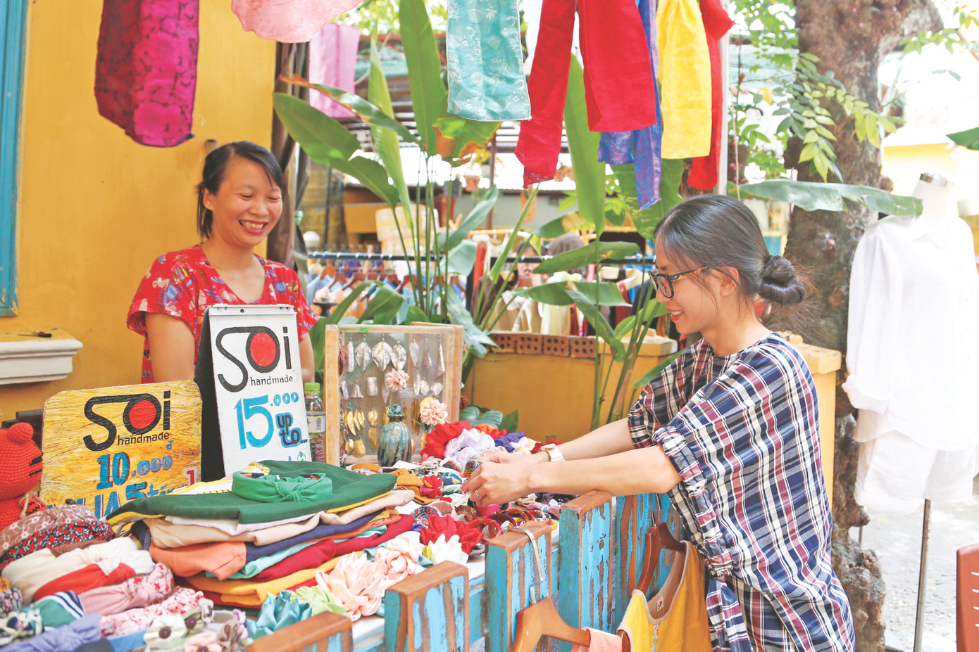 Chị Trương Nguyễn Hoài An, người sáng lập Chợ phiên thủ công (bên phải) hỗ trợ các cư dân của xóm bày biện, sắp xếp hàng hóa. Ảnh: Giang Thanh
