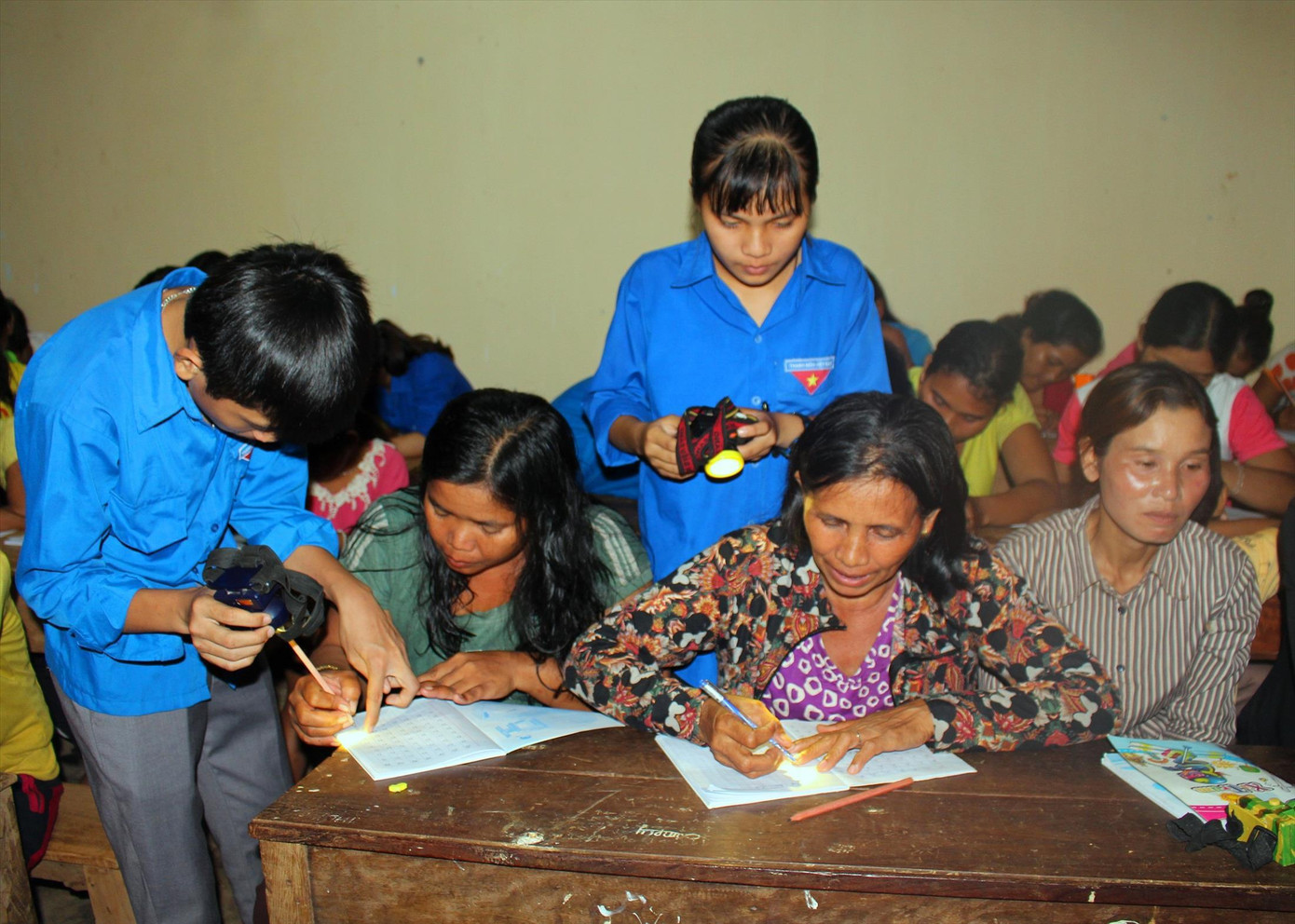 Thanh niên tình nguyện hướng dẫn phụ nữ Êđê viết chữ Thanh niên tình nguyện hướng dẫn phụ nữ Êđê viết chữ