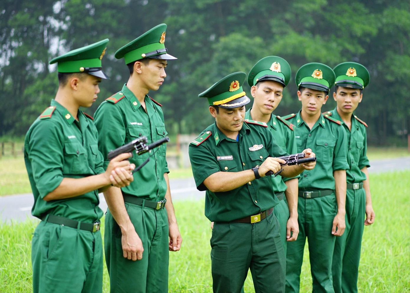 Thiếu tá Phạm Ngọc Hoàng (thứ 3 từ trái sang) hướng dẫn học viên bắn súng ngắn với thiết bị do anh nghiên cứu, chế tạo. ẢNH: PV