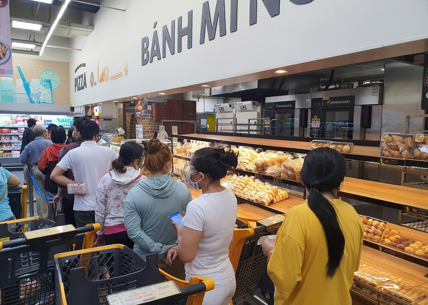 Bên trong siêu thị, người dân xếp hàng chen chúc mua đồ ăn, nhiều sản phẩm đã trở nên khan hiếm, 'cháy hàng'.