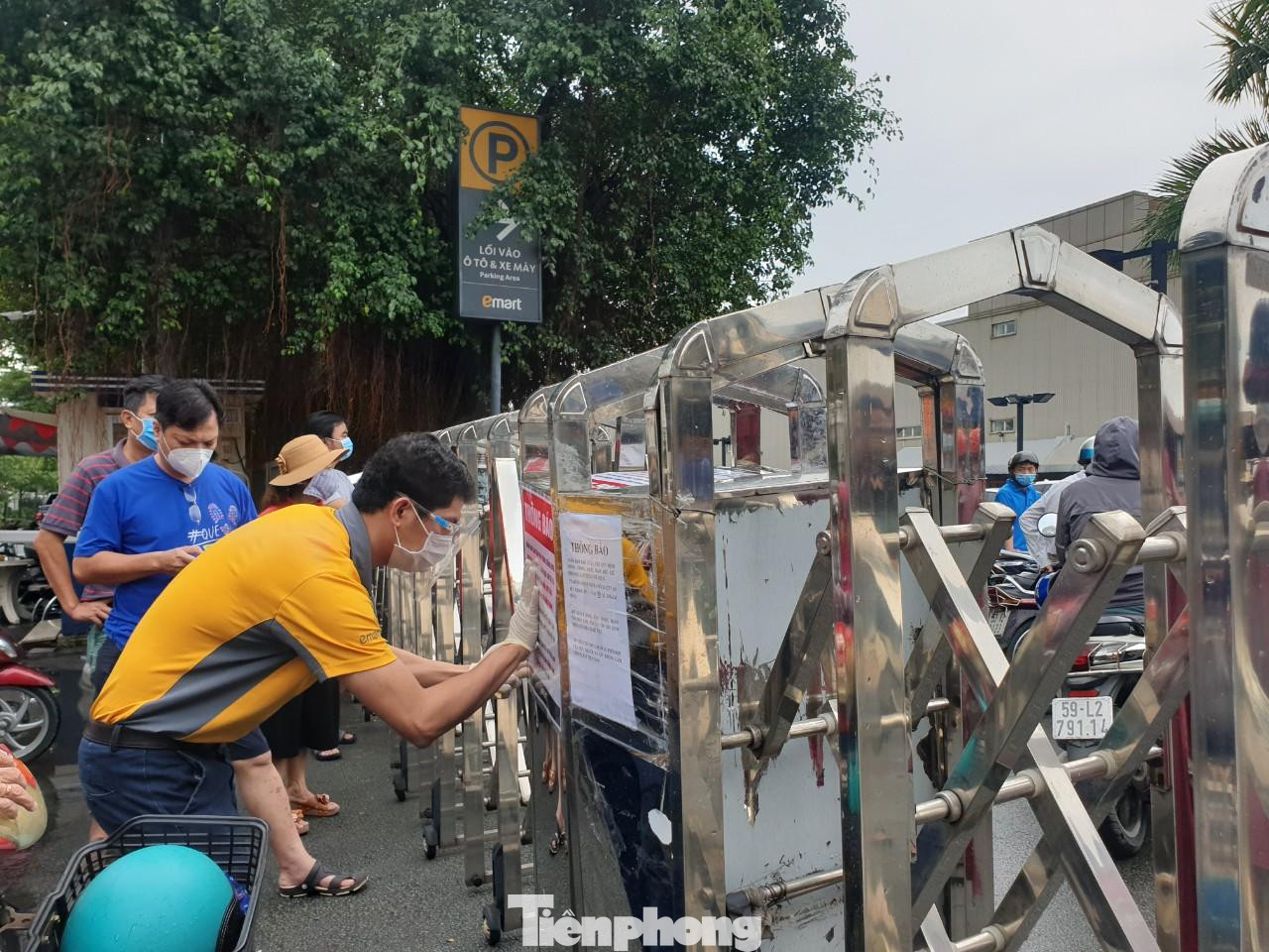 Nhân viên siêu thị dán thông báo về việc thực hiện giãn cách, yêu cầu người dân tuân thủ 5K khi đi siêu thị.