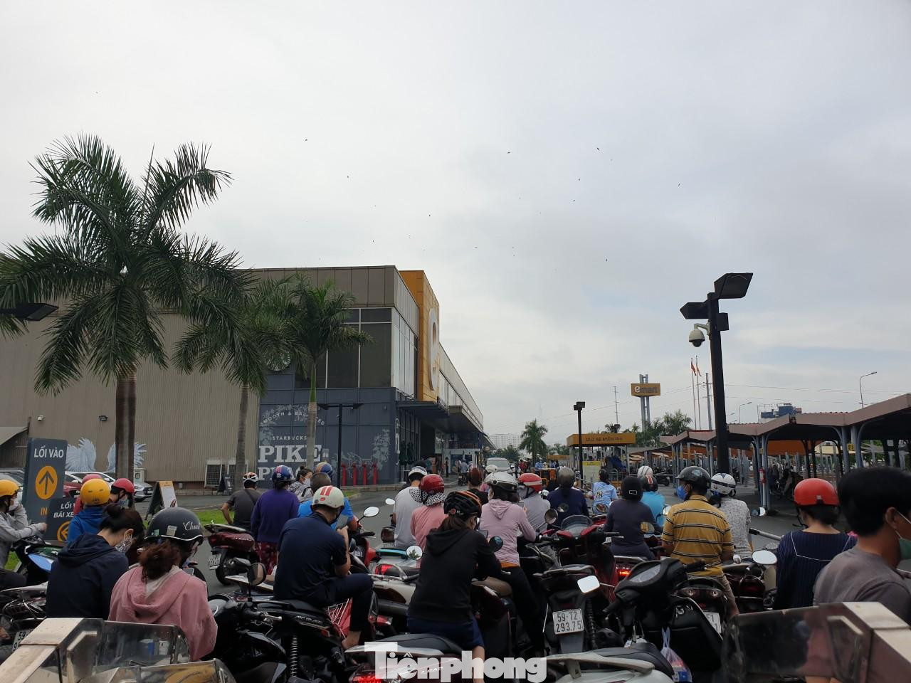 Tại khu vực cổng bên hông siêu thị, lực lượng bảo vệ chỉ cho từng đợt khách vào nên nhiều người đi xe máy xếp hàng chen lấn bên ngoài.