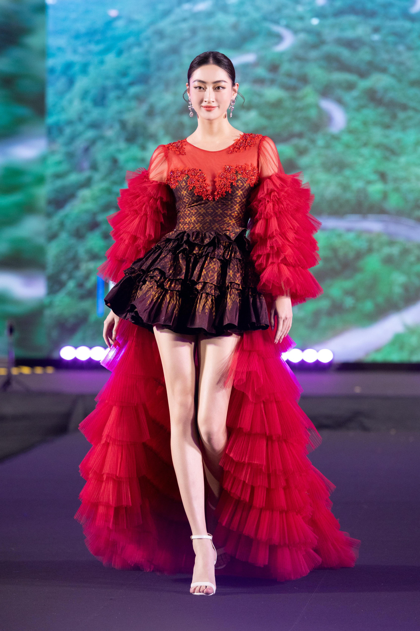 Khác với các người đẹp khác, Lương Thùy Linh không trình diễn áo dài. Cô diện thiết kế xếp ly độc đáo, khoe đôi chân dài quyến rũ trên sàn catwalk.