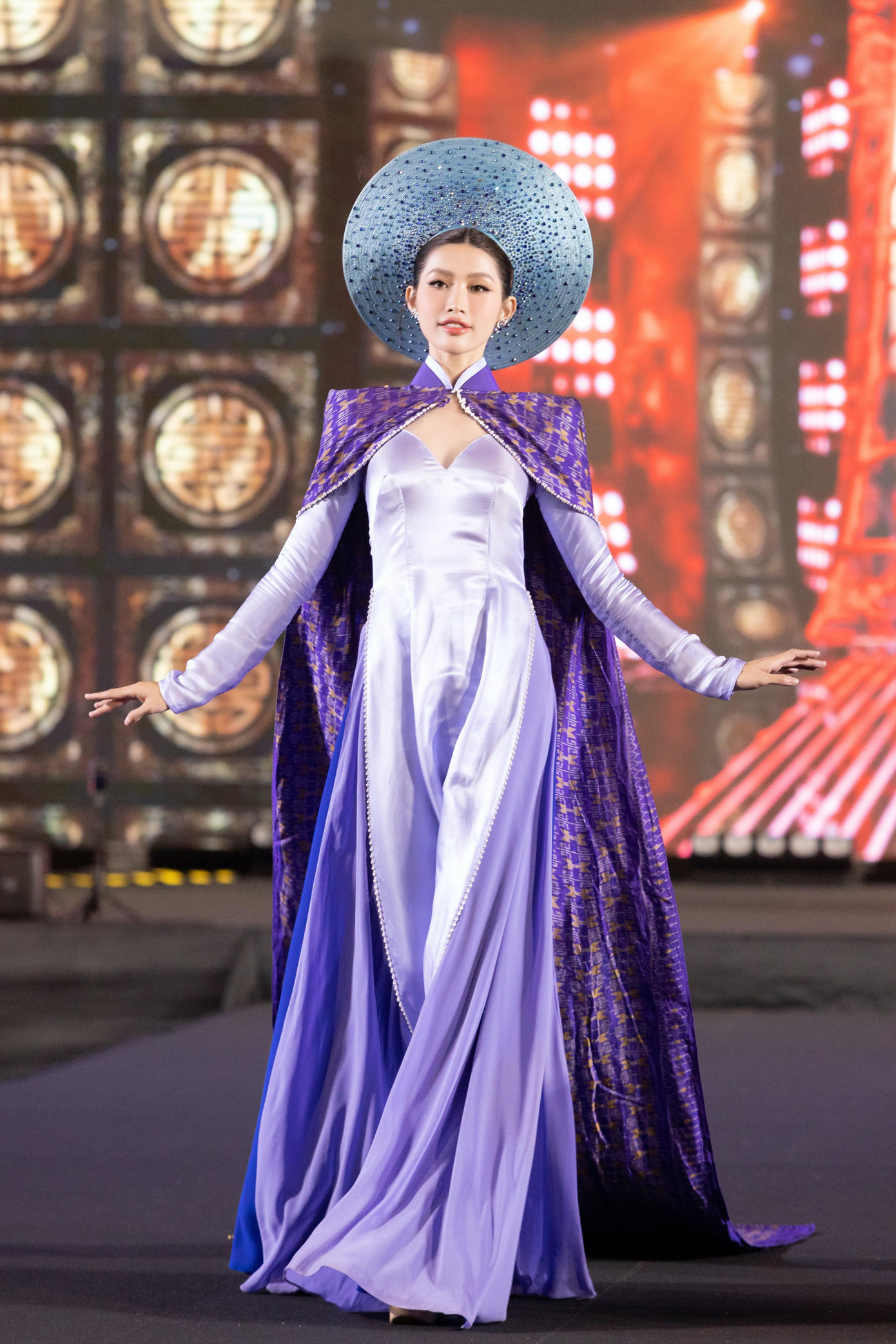 Á hậu Quỳnh Châu xuất hiện với vai trò first face trong một màn trình diễn. Cô diện áo dài màu tím kết hợp phần áo choàng lộng lẫy.