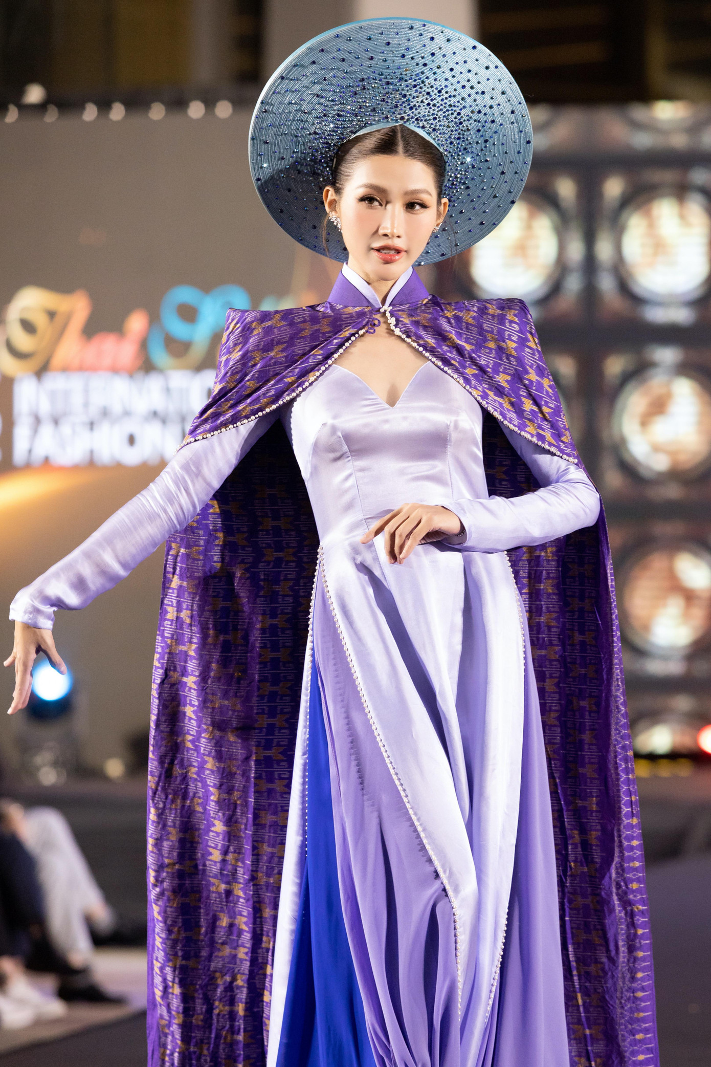 Á hậu Quỳnh Châu xuất hiện với vai trò first face trong một màn trình diễn. Cô diện áo dài màu tím kết hợp phần áo choàng lộng lẫy.