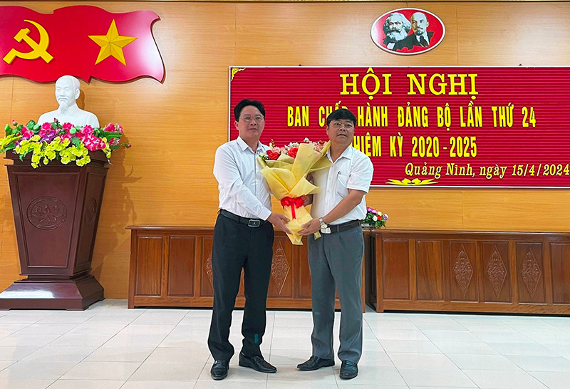 Ông Phạm Trung Đông (trái) nhận hoa chúc mừng của lãnh đạo huyện Quảng Ninh