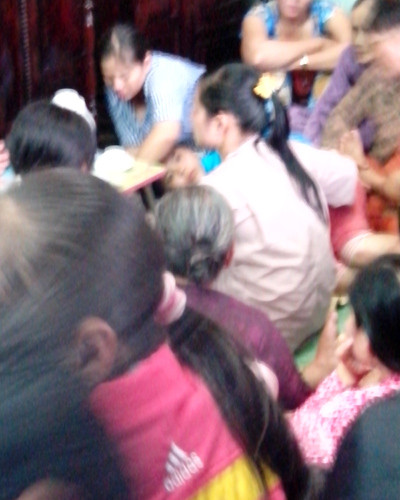 Võ Thị Hồng Ngọc tóc dài buộc cao, ngồi trước bàn nhỏ, quay mặt vào trong